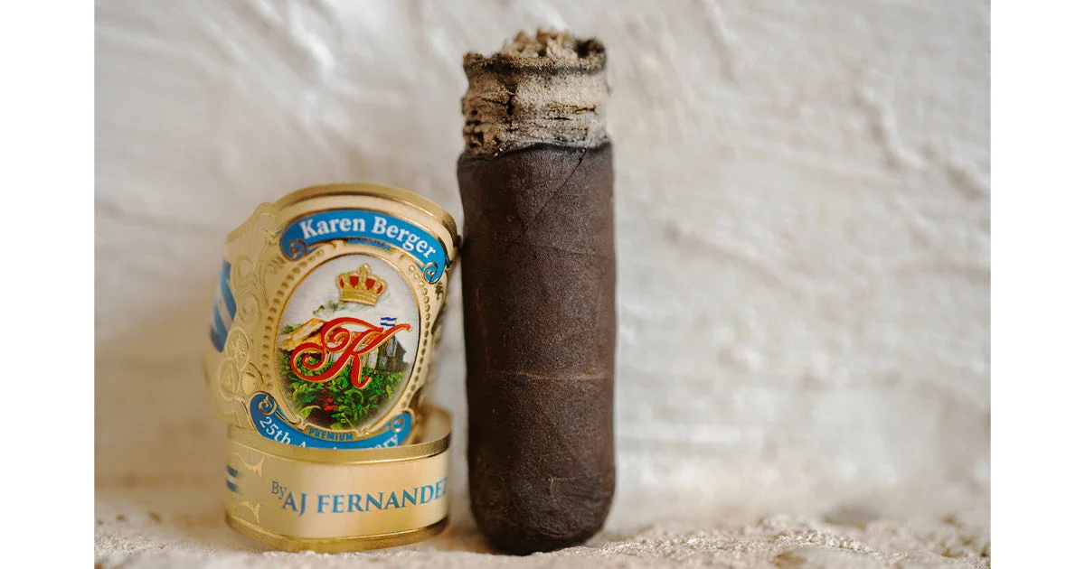 Charuto Karen Berger 25th Anniversary by AJ Fernandez com capa escura oleosa e cinza branca firme ao lado da anilha