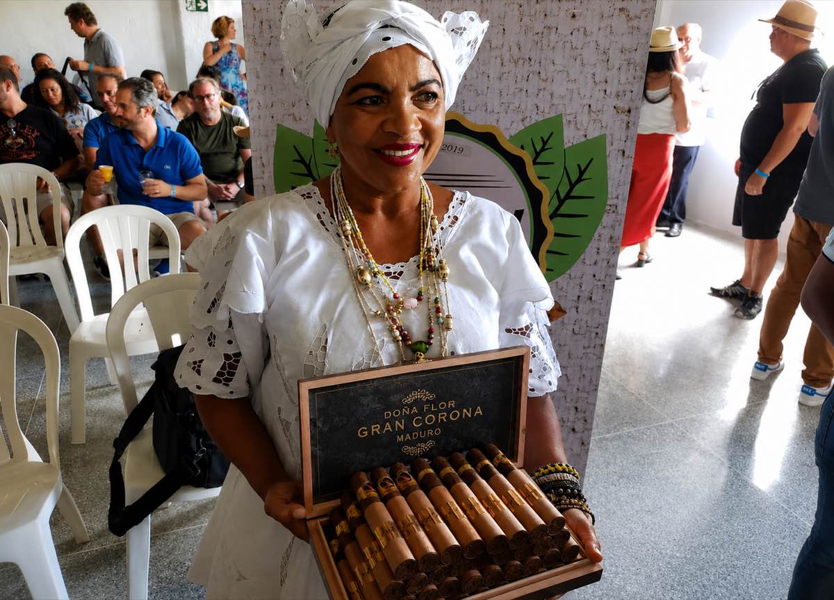 Caixa de charutos Dona Flor Gran Corona Maduro apresentada por baiana em traje típico durante evento da Menendez Amerino