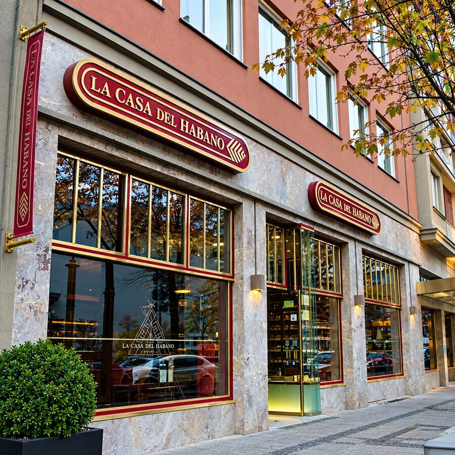 Fachada de uma La Casa del Habano com letreiros vermelhos e dourados e vitrines de charutos